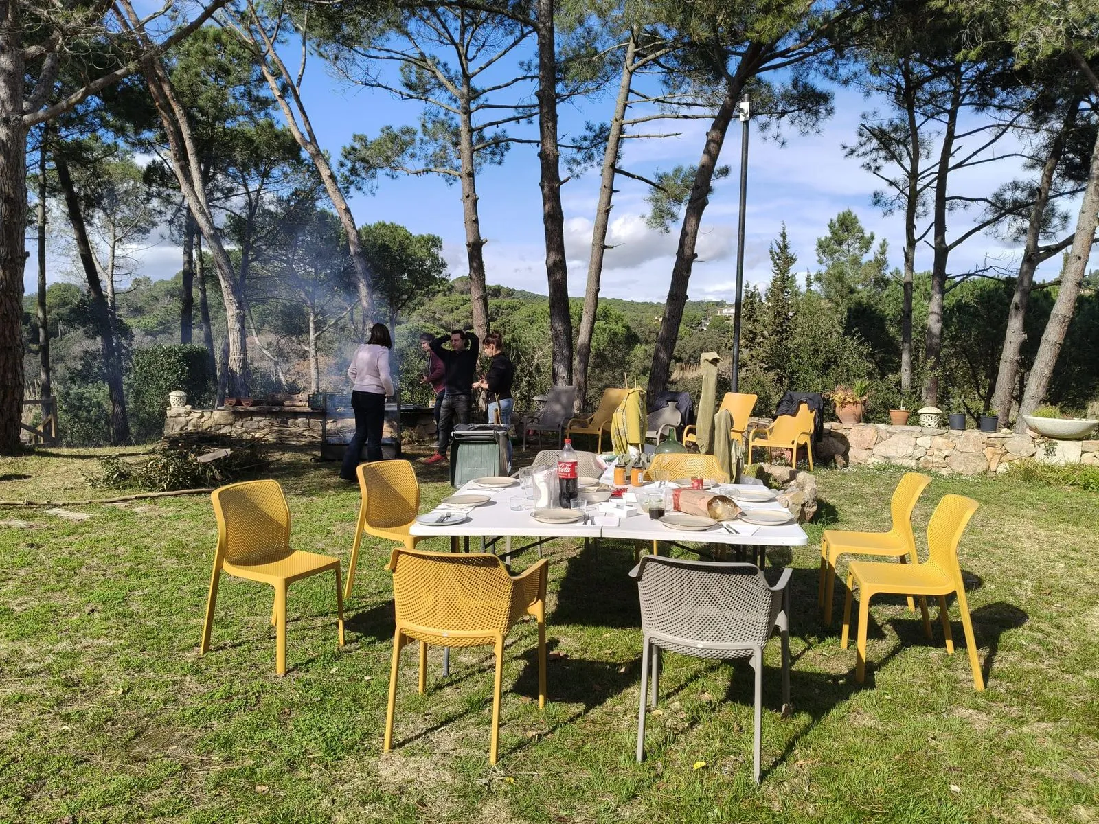 Mesa preparada bajo los pinos durante una calçotada en la finca