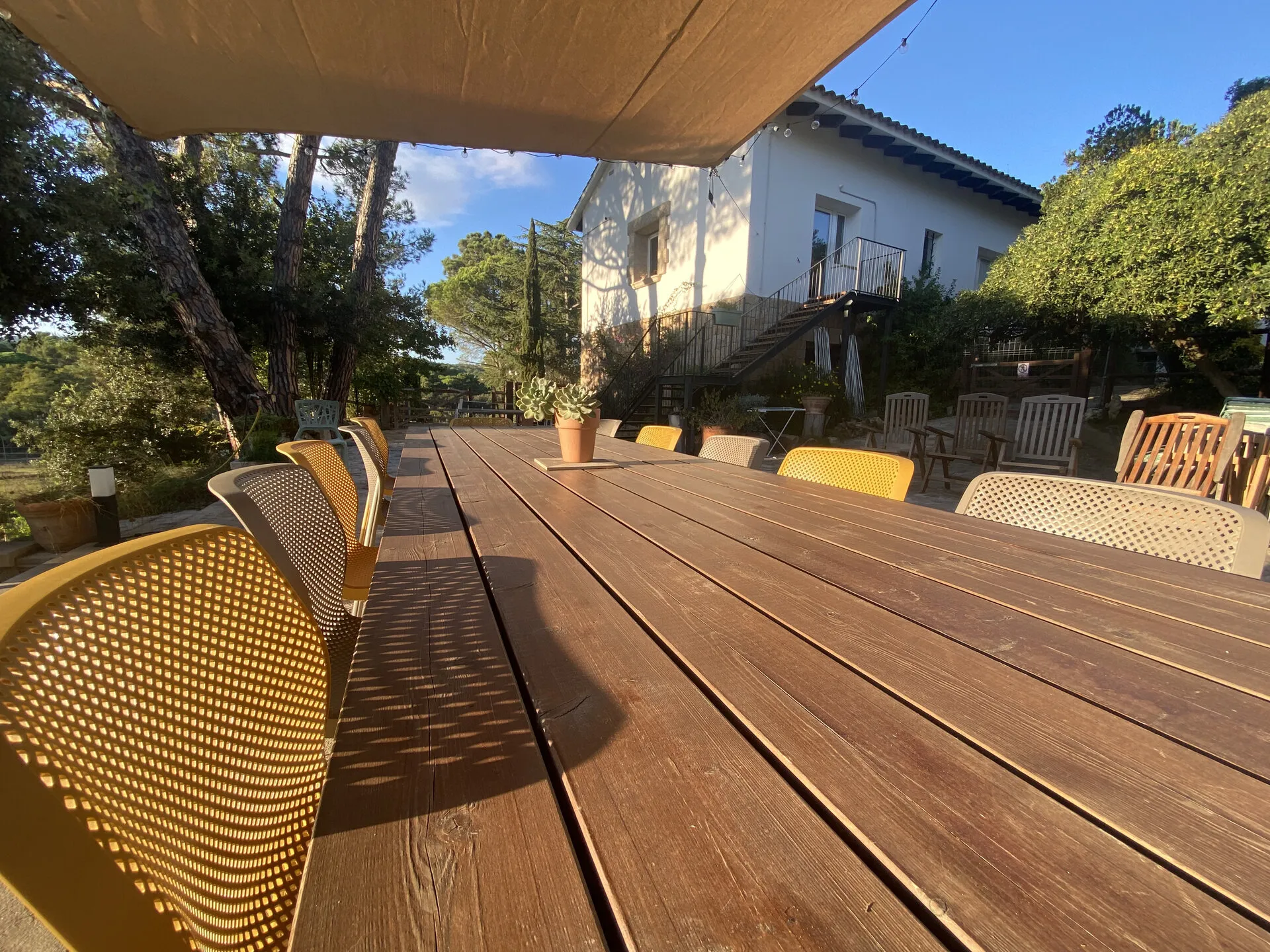 La mesa larga de la terraza, a la sombra del toldo