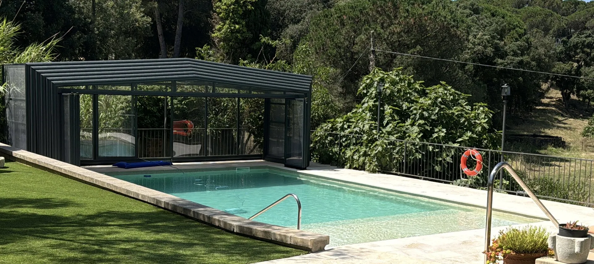 La piscina descubierta en verano, con la cubierta recogida al fondo