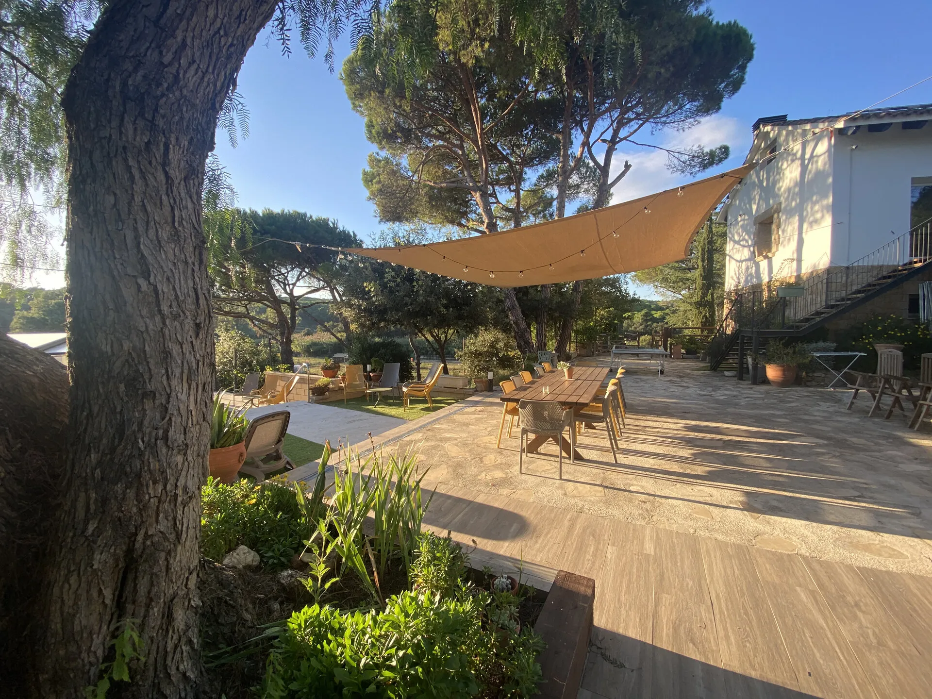La terraza con la vela de sombra y la mesa exterior, junto a la casa