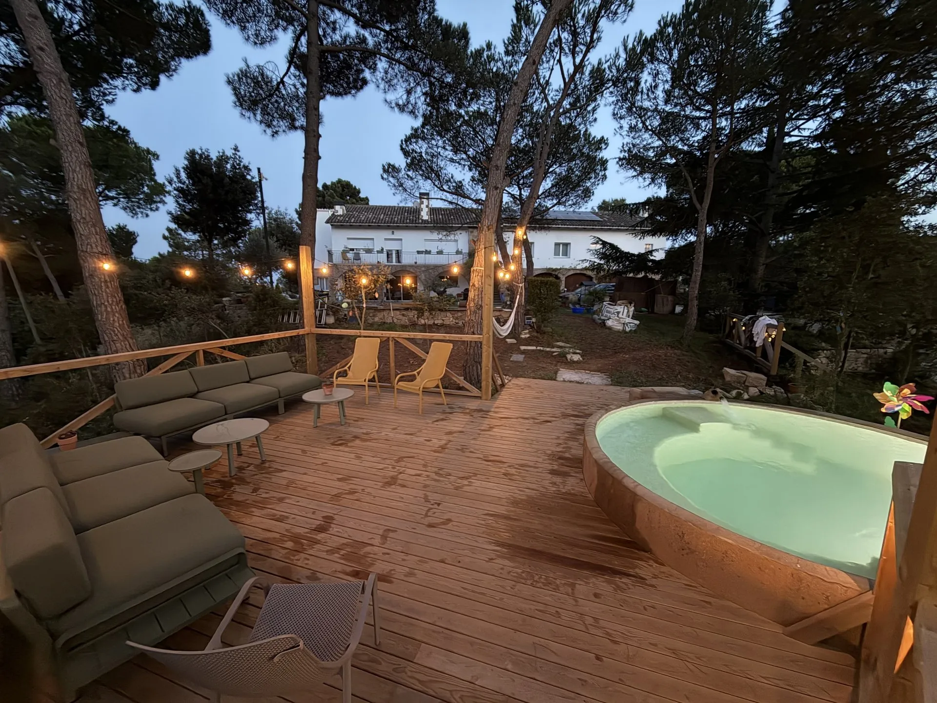 La terraza chillout de noche, con la piscina y la casa iluminada al fondo