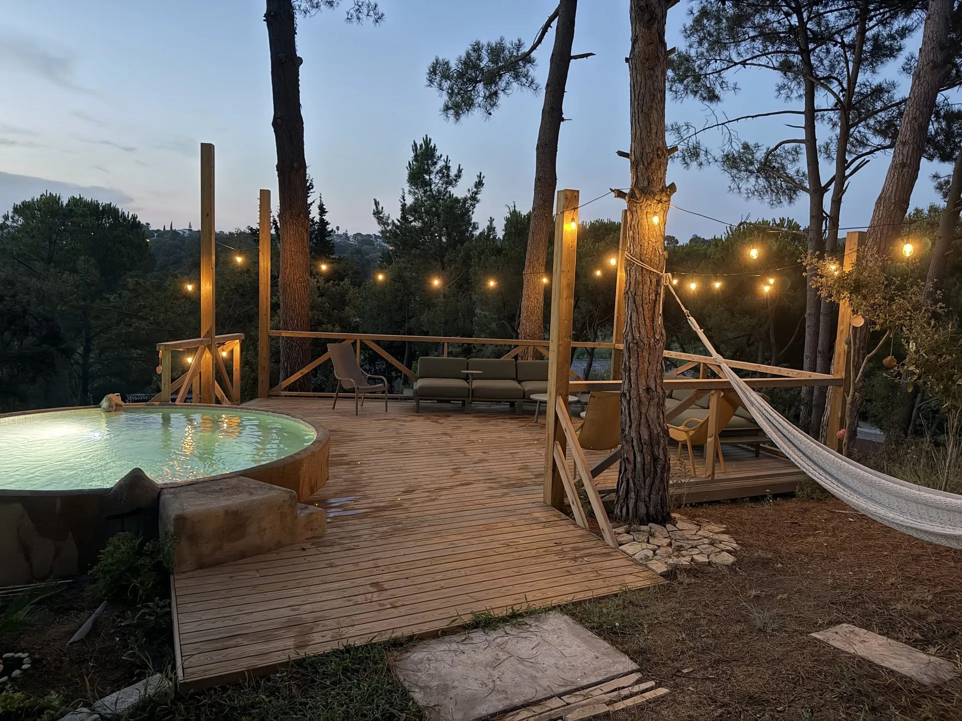 La piscina redonda de noche, con la tarima del chillout y la hamaca al fondo