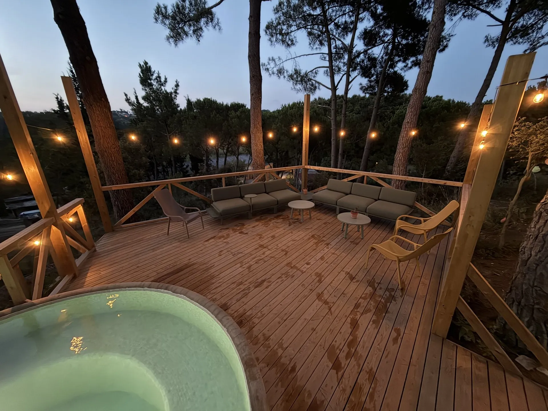 Los sofás del chillout de noche, con las guirnaldas encendidas entre los pinos