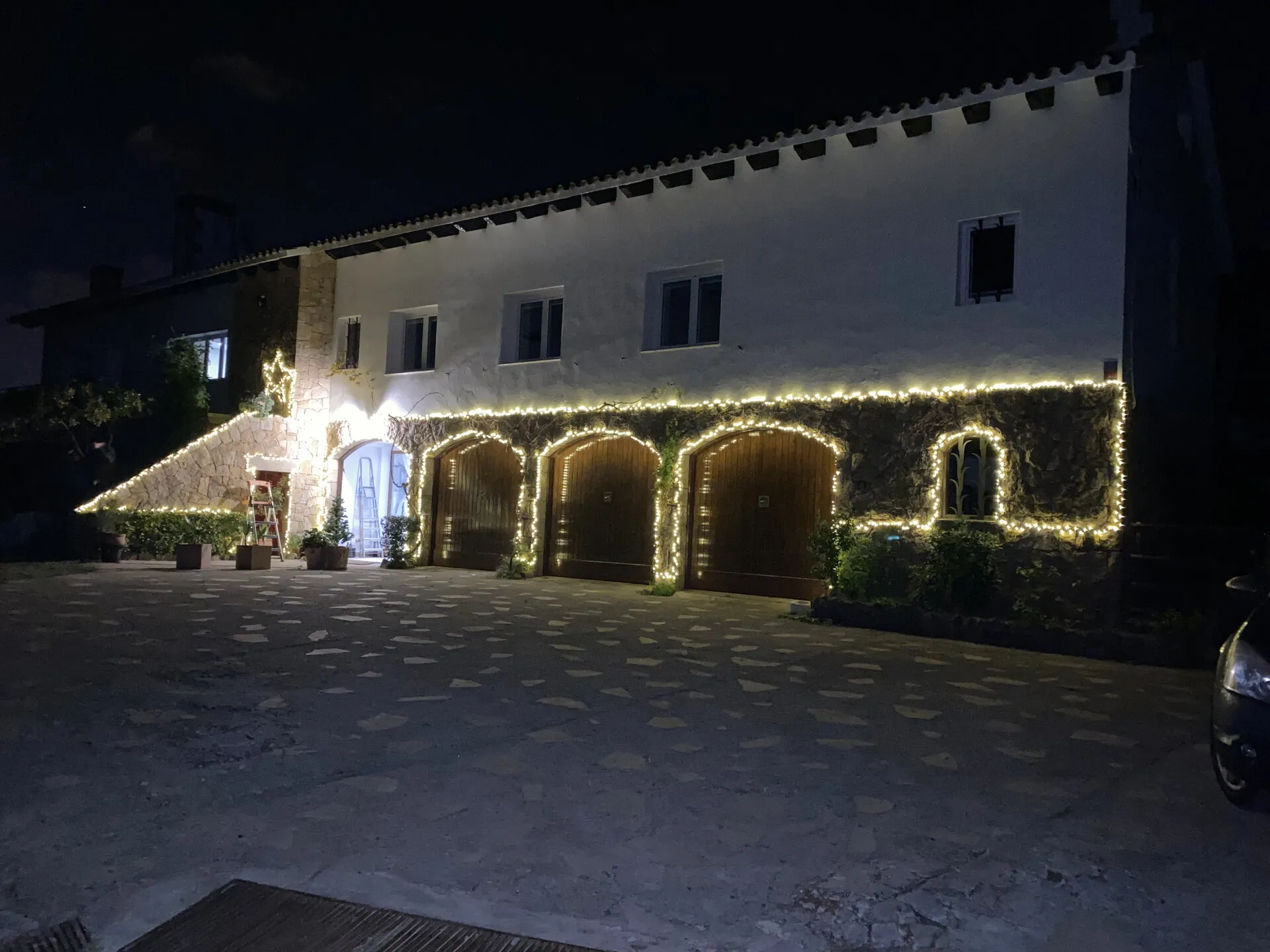 La fachada iluminada de noche, con las tres puertas de madera