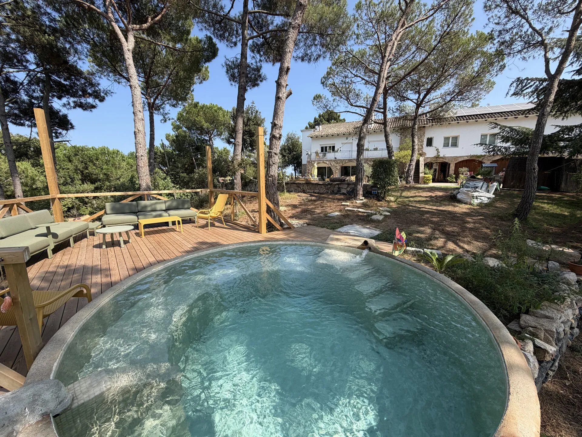 La piscina redonda de agua salada en la tarima de madera, con la casa al fondo