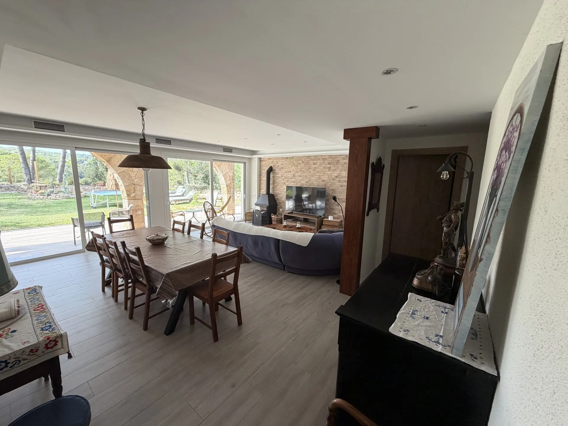 La mesa del comedor con el salón al fondo y el jardín tras los ventanales